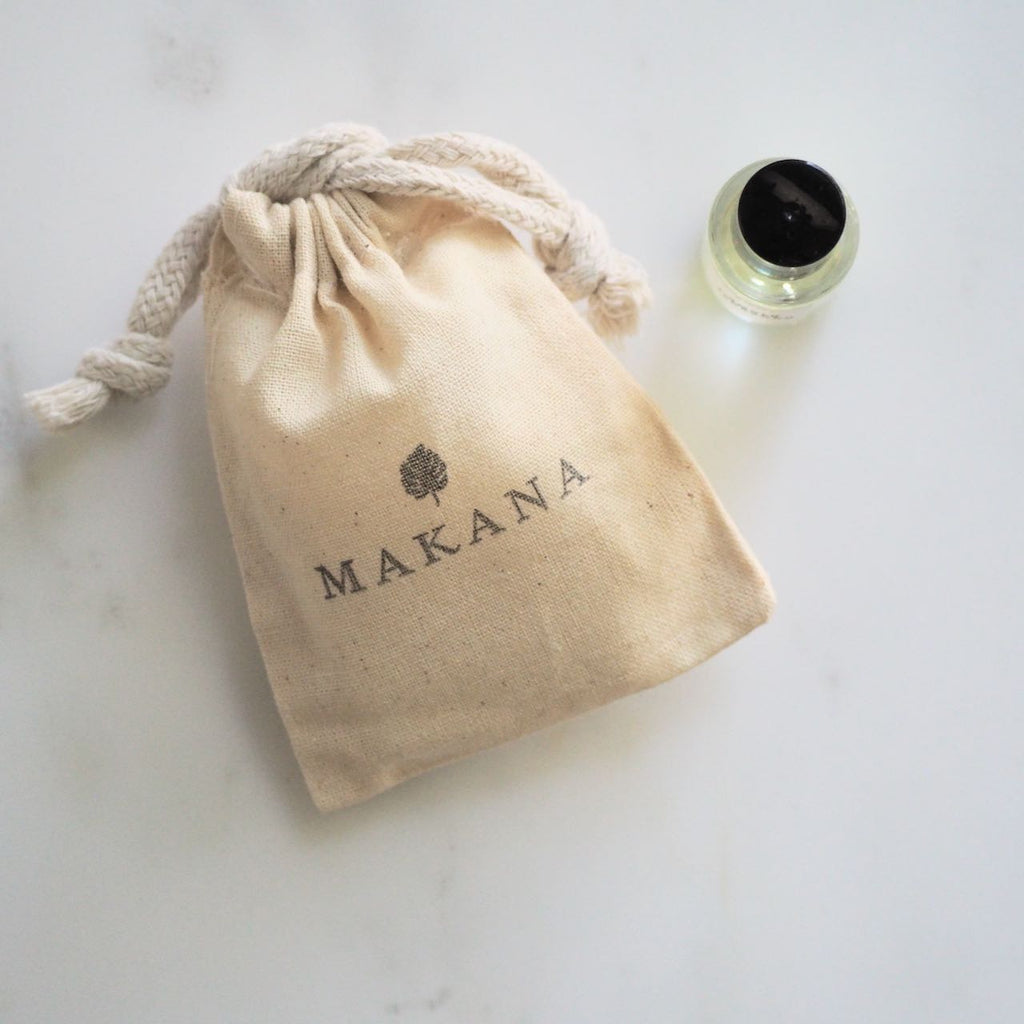 Makaka Perfume on white next to a muslin pouch with the name Makana stamped on it